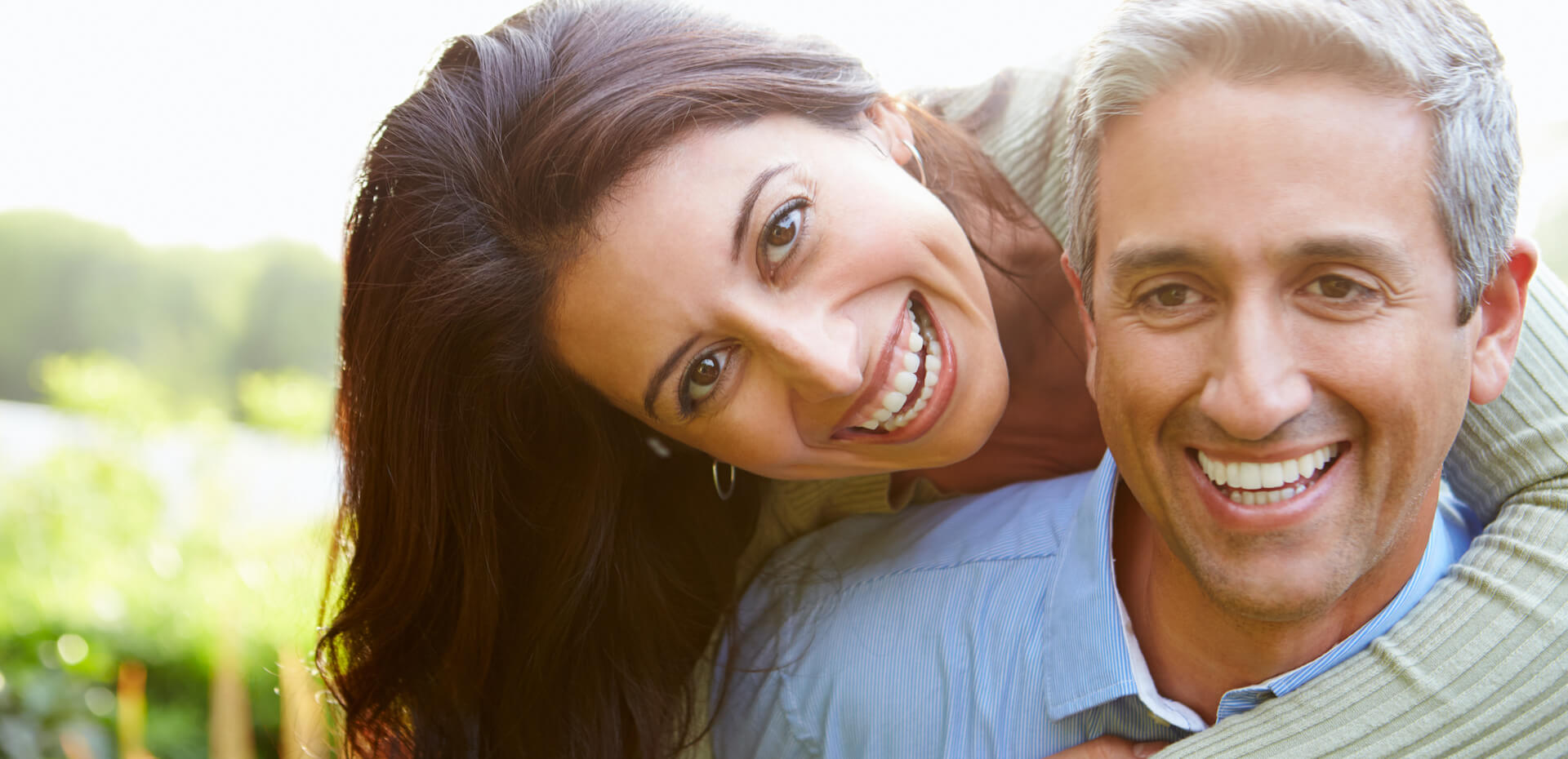 Happy couple hugging outdoors who may be refractive lens exchange patients