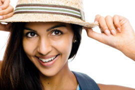 Happy woman adjusting brim of straw hat