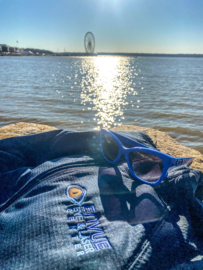 Photo of sunglasses on a jacket with an Envue logo at the beach.